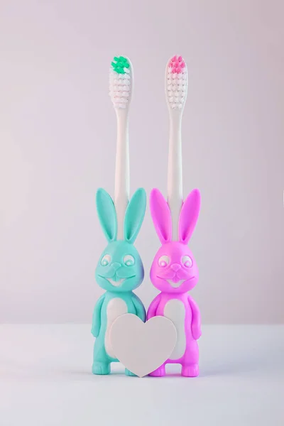 Escovas de dentes infantis em uma forma de coelhos bonitos em um fundo branco isolado. Dois coelhos com coração em branco . — Fotografia de Stock