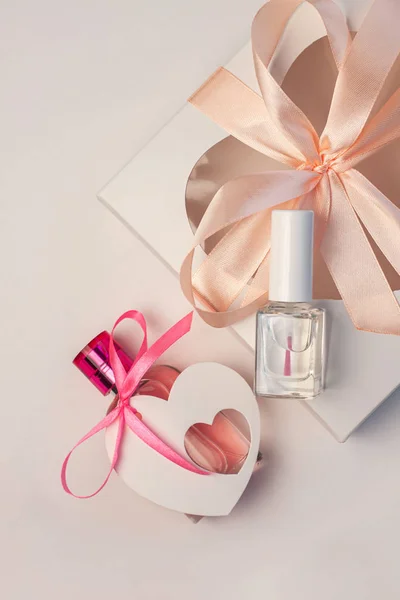 Día de San Valentín concepto creativo flatlay. maqueta de caja de regalo, botella de perfume rosa y esmalte de uñas con cinta de tarjeta de corazón —  Fotos de Stock