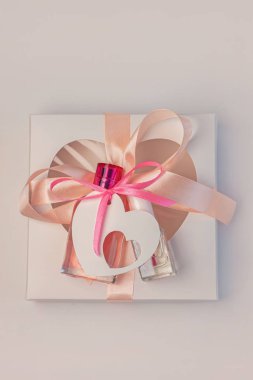 Sevgililer Günü yaratıcı konsepti. Hediye kutusu modeli, pembe parfüm şişesi, beyaz arka planda kurdeleli tırnak cilası.