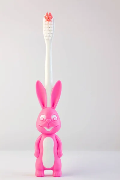 Cepillo de dientes para niños en forma de lindo conejito rosa sobre fondo blanco aislado.Conejo con cara sonriente, pancarta de odontología — Foto de Stock