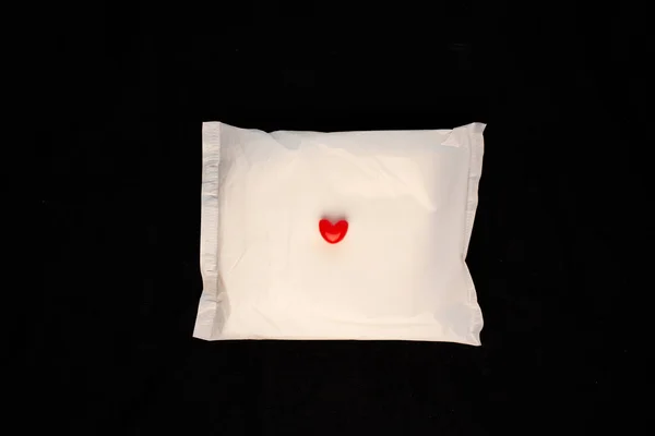 Unregelmäßiger Zeitraum Konzept. Menstruationszykluskissen mit roten Herzen auf schwarzem Hintergrund. Menorrhagie oder starke Menstruation — Stockfoto