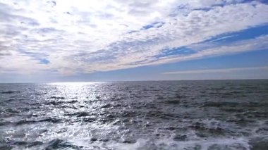 Deniz dalgaları ağır çekimde çarpıyor. Güzel mavi ve beyaz gökyüzü. Döngülü okyanus yüzeyi dokusu. Beyaz köpüklü mavi su boş sahilin üzerinde uçuyor. Güneşli bir günde köpüren ve sıçrayan dev bir dalga,
