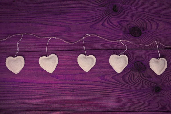 Valentines Day concept design flat lay.Eco linen hearts garland on purple wooden background. Decorative white heart — Stock Photo, Image