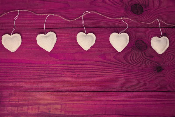 Valentines Day concept design flat lay.Eco linen hearts garland on purple wooden background. Decorative white heart — Stock Photo, Image