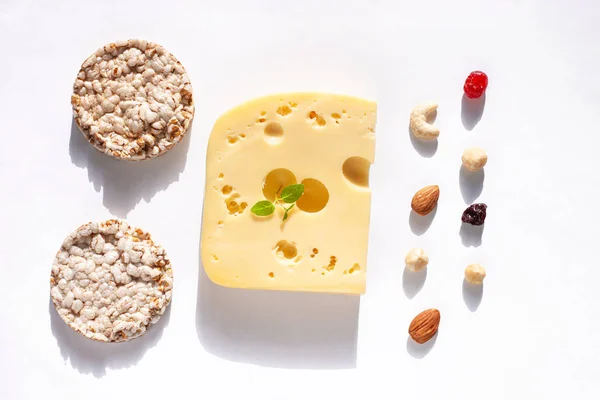 Creative healthy breakfast concept white background flat lay.Cheese,calcium rich food,nut, fruit, whole grain crispbread