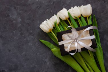 Beyaz lale çiçekleri ve siyah hediye kutusu. Metin 8 Mart Mutlu Kadınlar Anneler Günü için yer. Gümüş kurdeleli çiçek buketi, tebrik kartı. İnternet sitesi afişini üstten kopyala