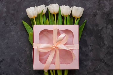 Beyaz lale çiçekleri ve üzerinde kurdele olan pembe hediye kutusu. 8 Mart Mutlu Kadınlar Günü için yer. Çiçek buketi tebrik kartı. Uzay web sitesi afişini kopyala