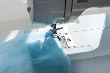 El yapımı Coronavirus hastalığına karşı yüz maskesi COVID-19 pandemisi. Bağcıklı dikiş makinesi, tıbbi malzeme sıkıntısı. Çözüm eksikliği, tozu, mikropları, ev yapımı virüs korumasını önler