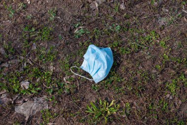 COVID-19 karantinası sırasında parktaki yeşil çimlerde tıbbi maske kullanılmış. Virüs bulaşma riski olan tehlikeli atıklar. Koronavirüs mikrobu yayılmış bir çöp. Bir salgın sırasında gündüz vakti Spring Street View.