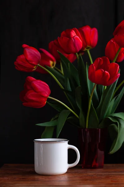 Biały Kubek Kawy Niesamowicie Kwitnących Czerwonych Tulipanów Bukiet Czarnym Tle — Zdjęcie stockowe