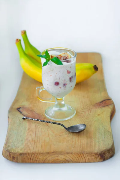 Yogurt Jelly Dessert with banana, strawberry, cocoa, fresh mint in a glass on wooden cut board. Healthy vegan sweet jello food.Vanilla agar-agar milk pudding low calories diet recipe, vertical banner.