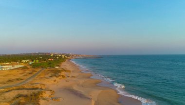 Sahilde gün doğumu. Güzel bir yaz manzarası. Kumda kayalar. Sudaki sakin dalgalar. Gökyüzündeki bulutlar.