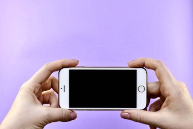 İki elinde de siyah ekran olan bir akıllı telefon. Mor arka planda mesaj için yer var..