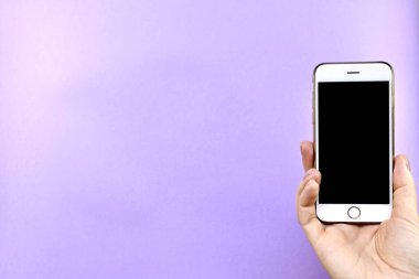 Elinde siyah bir ekranı olan akıllı telefon, mor bir arka planda..