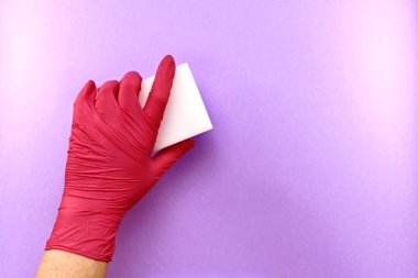  The left hand in a rubber glove, a gesture of erasing, removing something from a light purple surface, melamine sponge. clipart