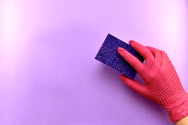  Lastik eldivendeki bir el, silme hareketi, açık mor bir yüzeyden bir şey çıkarmak, bir çamaşır süngeri..