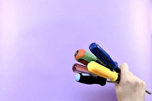 Kilka różnych w kolorze i kształcie śrubokrętów, zaciśnięty w pięści kobiecej ręki. — Zdjęcie stockowe