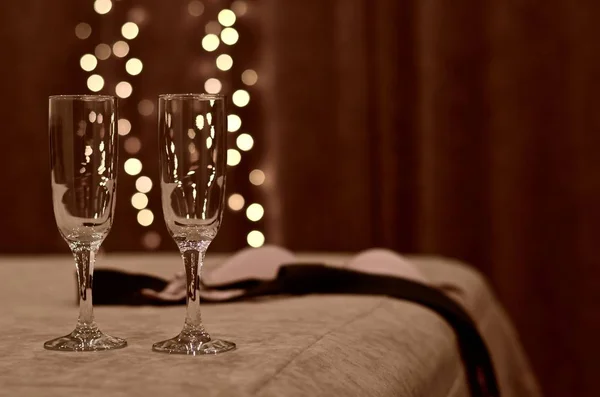Dois copos com luzes quentes de saída lateralmente na cama com um sutiã descartado e gravata . — Fotografia de Stock