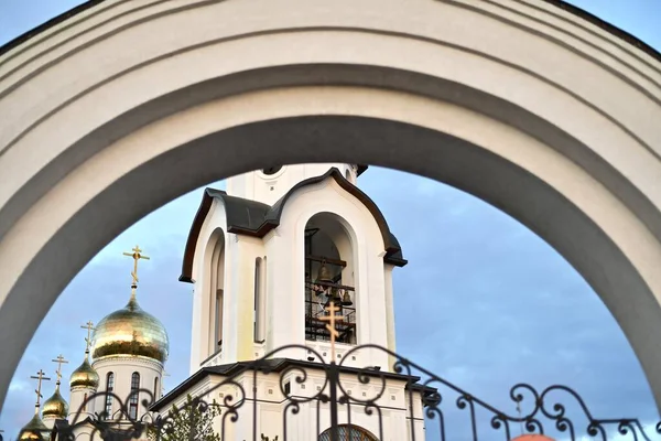 Pohled přes oblouk brány do zvonice katedrály a zlatých kopulí, proti modré obloze. — Stock fotografie