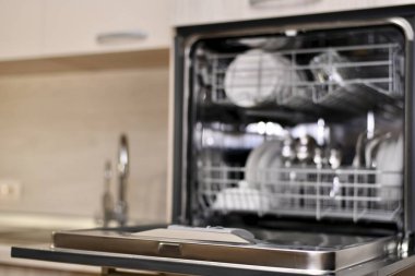  Lavabo seviyesinde açık bulaşıkları olan bir bulaşık makinesi, kurutma makinesi ve iki musluk, Bokeh ile bulanık bir arka plan olarak..