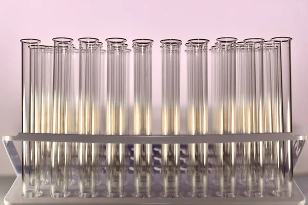 Transparente Reagenzgläser in einem Tablett auf lila Hintergrund, gefüllt mit goldenem Licht. — Stockfoto