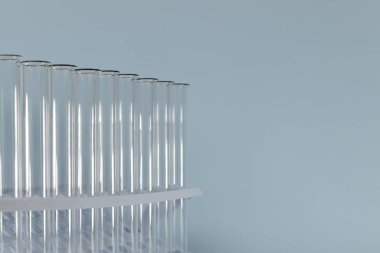 Sol taraftaki mavi arkaplanda şeffaf bir test tüpü parçasının yatay görüntüsü.