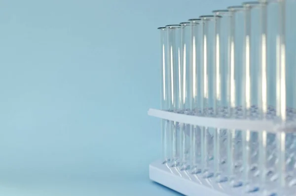 Ein horizontales Bild entfernter transparenter Reagenzgläser in einem Tablett auf blauem Hintergrund von rechts. — Stockfoto