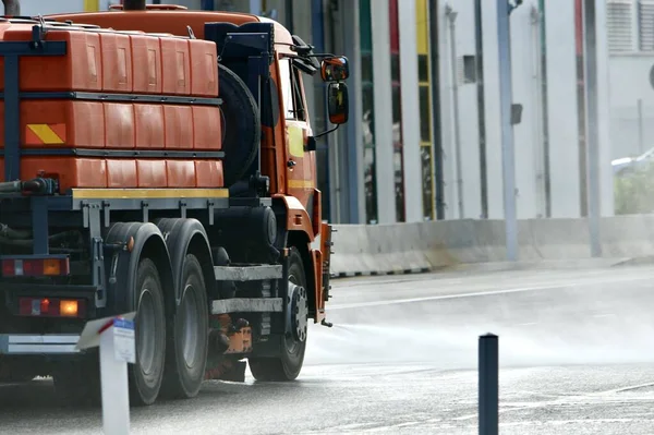 A machine with a high volume capacity is washing the road surface with a high-pressure jet.