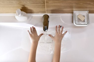 İki çocuk elleri avuçlarını açıp lavabonun üzerine su dökerek uzandı..