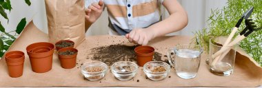 Çocuk, bahçedeki bahçe eşyalarının arka planında ellerini uzattı. Bir avuç içi sağ el yere yapıştı ve tencereyi dolduracak..