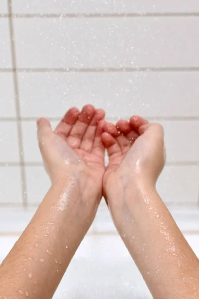 子供の手は 中央に伸ばし 浴室の水の滴の下で清潔さと新鮮さをお楽しみください — ストック写真
