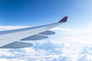 Bulutlardaki uçak penceresinden, açık mavi gökyüzünden. Bir uçağın penceresinden bak. Uçan bir uçağın kanadı. Güzel güneşli hava.