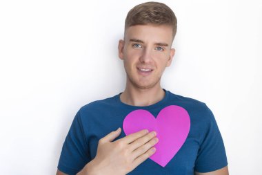 Yakışıklı bir adam, Sevgililer Günü 'nü göğsünde tutuyor, Sevgililer Günü kartı, kırmızı ya da pembe tebrik kartı olan genç bir adam. Uzayı kopyala Sevgililer Günün kutlu olsun. Duygular, aşk, ilişkiler