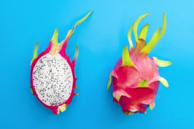 Ejderha meyvesi, 2 2 olgun pitaya veya egzotik tropikal pitahaya, tatlı kaktüs ikiye bölünmüş ve tüm meyve mavi arka planda. Üst Manzara. Yaz, sağlıklı taze yemek, vegan ya da vejetaryen diyet kavramı.
