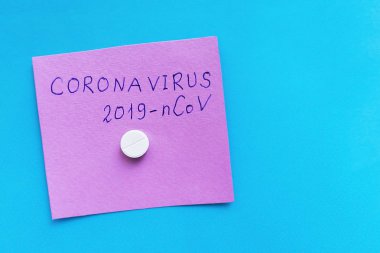 Coronavirus 2019-ncov 'un el yazısı. Pembe ve mavi arkaplanlı, beyaz bir hap, tablet. Çin 'den yeni Wuhan Coronavirus hastalığı, zatürree virüsü koruma kavramı.. 