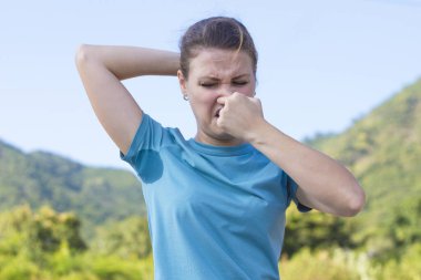 İğrenç bir kız, terli tişörtlü bir kadın, ıslak kirli koltukaltları, kötü ter kokusu. Deodorant kullanıyor, hoşnutsuz bayan kaşlarını çatıyor, kötü koku yüzünden burnu parmaklarıyla tıkıyor. Hiperhidroz. 