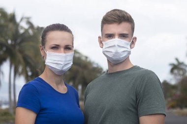 Güzel bir çift, erkek, koruyucu steril tıbbi maskeli kız Asya caddesindeki kameraya bakıyor. Hava kirliliği, virüs, yeni Çin salgını koronavirüs konsepti. Erkek ve kadın..