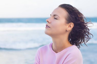 Güzel bir kızın profil portresi, derin, derin deniz havası soluyan, gözleri kapalı yaz havasının tadını çıkaran rahat genç bir kadın. Sakinlik, meditasyon, barış, mutluluk kavramı.