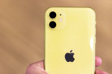 Kuala Lumpur, Malezya - 28.02.20: yeni sarı iPhone 11, çift kameralı 11. Apple cep telefonu akıllı telefonunun arkası. Fotoğrafı kapat. Modern teknoloji, ahşap kahverengi arka plan bulanık