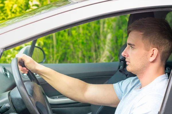 Jonge knappe geconcentreerde man, ongebonden bestuurder, serieuze man die een auto bestuurt, autowiel vasthoudt, geniet van een road trip. Zijaanzicht. — Stockfoto