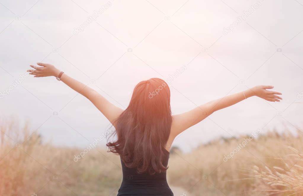 Portrait of happy and enjoying young woman on a meadow on a sunn
