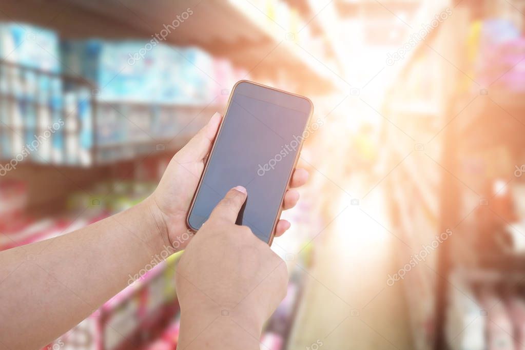 women use mobile phone and blurred image of supermarket. shoppin