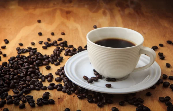 Grão de café e café preto no fundo textura de madeira. breakfa — Fotografia de Stock
