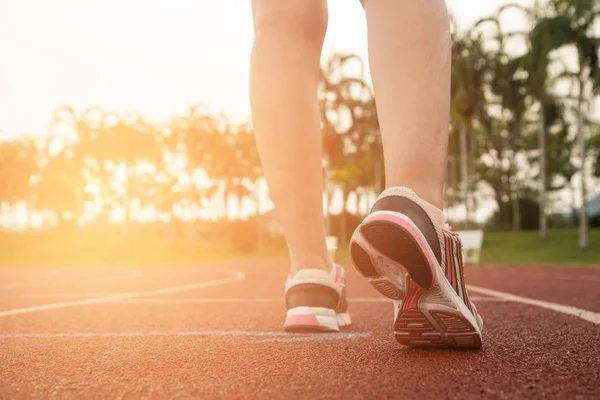 Ung kvinna löper under solig morgon på stadion spår. Healt — Stockfoto