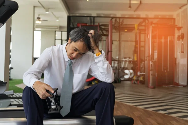 Businessman busy or failure looking hourglass sitting on treadmi