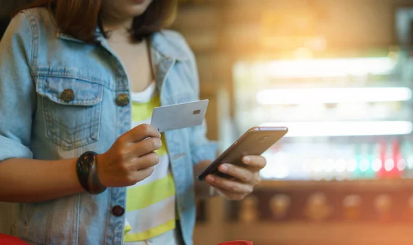 Женщина использует смартфон и держит кредитную карту с покупками онли — стоковое фото