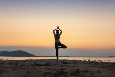 Deniz kenarında gerçeküstü gün batımında yoga yapan bir kadın. sağlıklı konsept ve egzersiz.