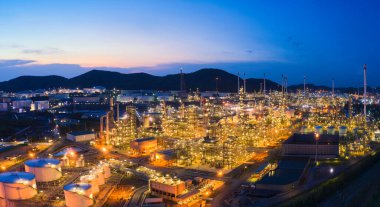 Petrol rafineri fabrikası endüstrisi ile petrol depolama tankının hava görüntüsü. Güneş batımında ve alacakaranlıkta petrol rafinerisi. Fabrika konsepti ve ulaşım. Panorama resmi.