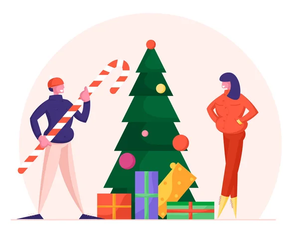 Regalos y dulces de Nochebuena. Hombre sosteniendo enorme bastón de caramelo y la mujer en ropa caliente de pie en el árbol de Navidad decorado — Vector de stock