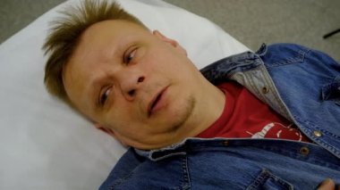 Doktor muayenehanesindeki kanepede oturan bir adam.